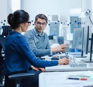 A technical software developer explains some major features to a female coworker.