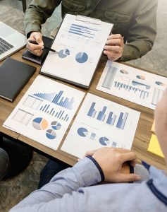 Group of business people having a discussion on a data chart with a laptop diary placed on a brown table